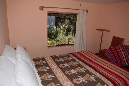 1 dormitorio con cama y ventana en Allpa Tika Lodge, en Ocosuyo