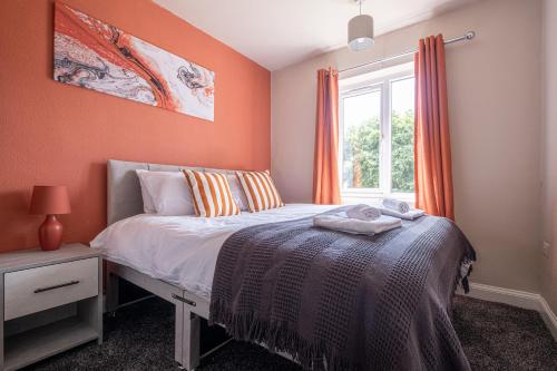 sypialnia z pomarańczowymi ścianami, łóżkiem i oknem w obiekcie Stunning Home Ideal for Business - Free Parking w mieście Birstall
