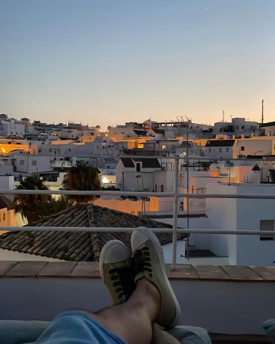 a person sitting on the ledge of a building with their feet up at Almaraz11 in Vejer de la Frontera