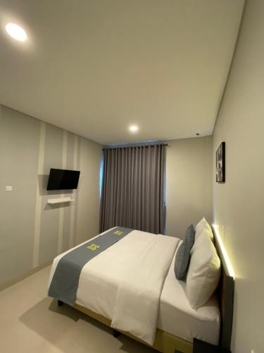 een slaapkamer met een bed en een televisie. bij Ghurfati Hotel Wedana in Jakarta