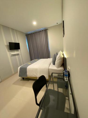 a hotel room with a bed and a glass table at Ghurfati Hotel Wedana in Jakarta