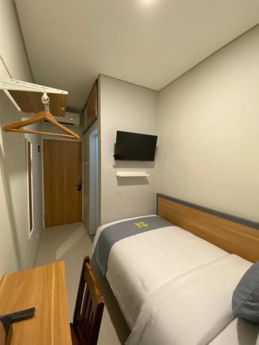 a small room with a bed and a table and a tv at Ghurfati Hotel Wedana in Jakarta