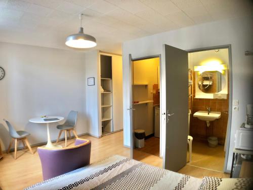 a bedroom with a bed and a table and a kitchen at Résidence Thermotel in Bourbonne-les-Bains
