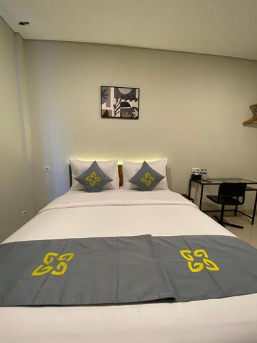a bed with yellow and blue pillows on it at Ghurfati Hotel Wedana in Jakarta