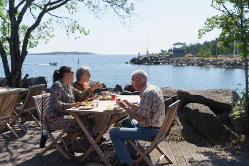a group of people sitting at a table by the water at Femöre Marina in Oxelösund