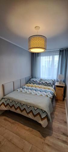 a bedroom with a bed and a chandelier at Apartament w Gdańsku 1 km od plaży in Gdańsk