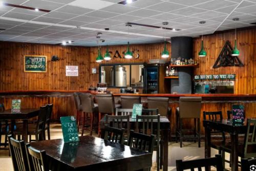 um restaurante com paredes e mesas e cadeiras de madeira em Roni’s place em Bnei Yehuda