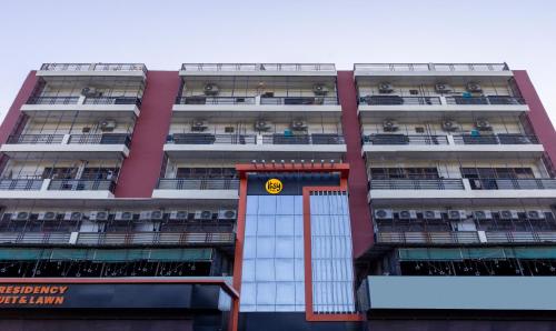 a tall pink building with a yellow sign on it at Itsy By Treebo - Kashi Grand, BHU in Varanasi