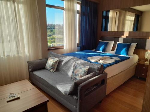 a bedroom with a bed and a couch and a window at FALCON PalaS OTEL in Istanbul