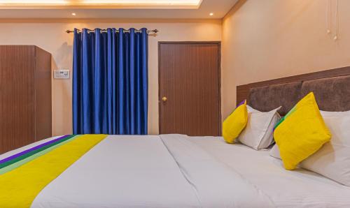 a bedroom with a large bed with yellow and blue curtains at Itsy Hotels Kashi Grand, BHU in Varanasi