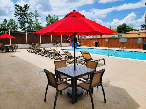 a table with a red umbrella next to a pool at Best Western Laurel in Laurel