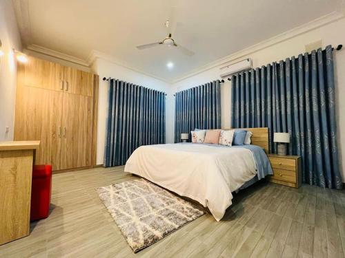 1 dormitorio con 1 cama grande y cortinas azules en WellingManor Apartments - Luxury, en Accra