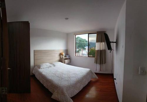 a white bedroom with a bed and a window at Buena Vista in Cuenca