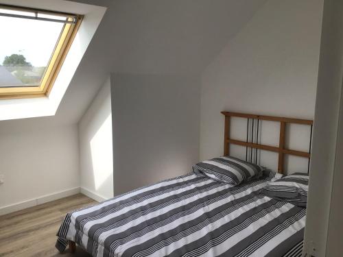 - une chambre avec un lit avec des draps rayés et une fenêtre dans l'établissement Maison neuve, à Plouguerneau