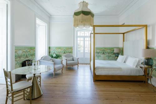 een slaapkamer met een hemelbed en een tafel en stoelen bij Palácio do Visconde - The Coffee Experience in Lissabon