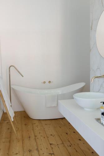 a white bathroom with a tub and a sink at Palácio do Visconde - The Coffee Experience in Lisbon