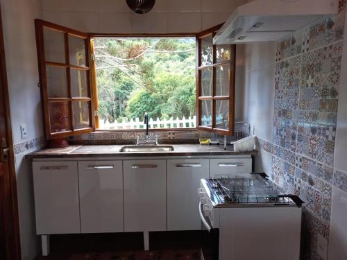 eine Küche mit einem Waschbecken und einem Fenster in der Unterkunft Chalé Mirante Da Guapiara in Aiuruoca