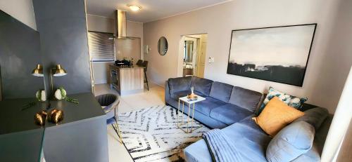 sala de estar con sofá azul y mesa en Staycation Sandton Apartment, en Johannesburgo