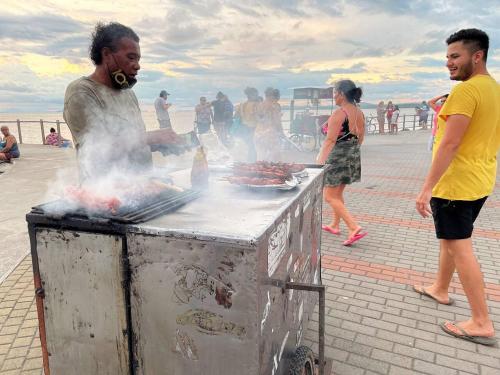 a man cooking meat on a grill on a beach at Relax at Pier Sands Casita#1 - Close to the Beach! in Puntarenas
