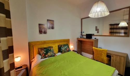 Un dormitorio con una cama verde y una silla amarilla en Saranda Center (above promenade), en Sarandë
