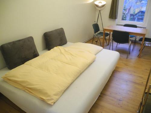 Cama blanca en habitación con mesa y sillas en Flow Home, en Berlín