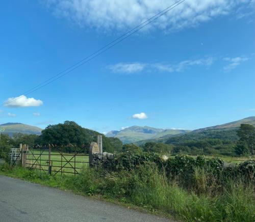 a road with a fence and mountains in the background at Snowdon Retreat in Llanrug