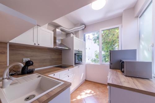 a kitchen with white cabinets and a sink at Perfect Spot Apartment in Varna City