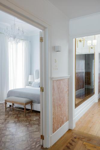 a white bedroom with a bed and a mirror at Palácio do Visconde - The Coffee Experience in Lisbon