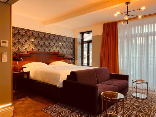 een slaapkamer met een groot bed en een bank bij Gatsby Hotel - Adults Only - Small Luxury Hotel - by F-Hotels in Blankenberge