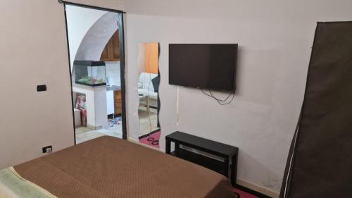 - une chambre avec un lit et une télévision murale dans l'établissement Chez Taii, à Serralta
