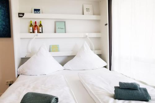 Bett mit weißer Bettwäsche und Kissen in einem Zimmer in der Unterkunft Hamburg 01 Modernes Apartment am Winterhuder Marktplatz Alster Stadtpark in Hamburg