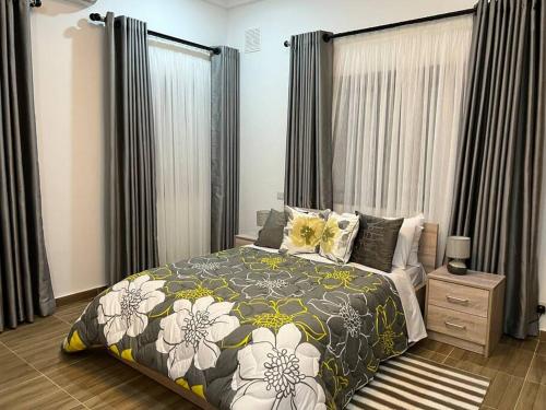 a bedroom with a bed with a floral bedspread at Luxury WellingManor Apartment in Accra