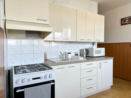 a white kitchen with a stove and a sink at Apartmán Simcity 2 in Banská Bystrica