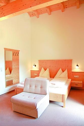 a bedroom with a bed and a chair and a mirror at Appartements Stockinger in Grossarl