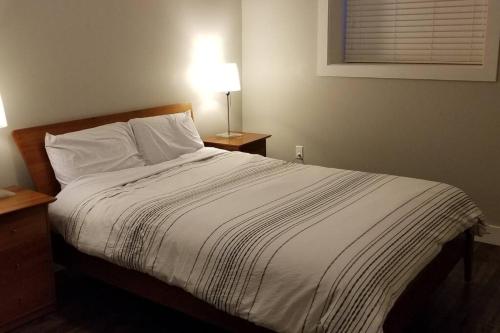 ein Schlafzimmer mit einem Bett mit einer weißen Decke und einer Lampe in der Unterkunft Basement Suite 1 queen bedroom(Brand New House) in Coquitlam