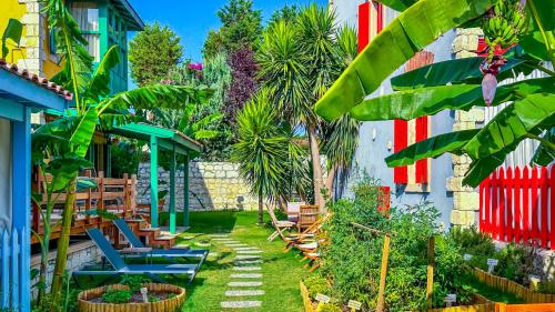 un jardin avec des chaises et des palmiers en face d'un bâtiment dans l'établissement Banana Alaçatı Wellness Hotel - Adults Only, à Alaçatı