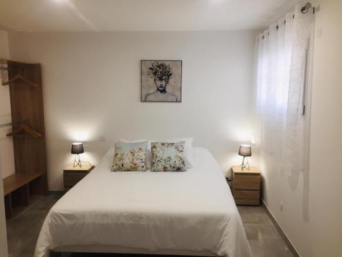 une chambre avec un grand lit blanc avec deux lampes dans l'établissement Les Acacias, à Caveirac