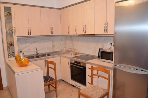 La cuisine est équipée de placards blancs et d'un réfrigérateur en acier inoxydable. dans l'établissement Maria Apartment, à Gjirokastër