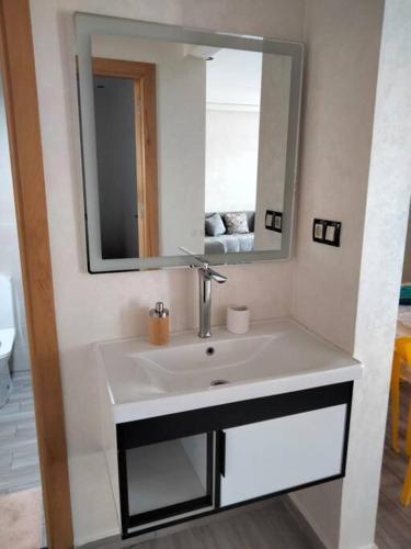 een badkamer met een wastafel en een spiegel bij Résidence flambant neuve 5min à pied de la plage in Saidia 