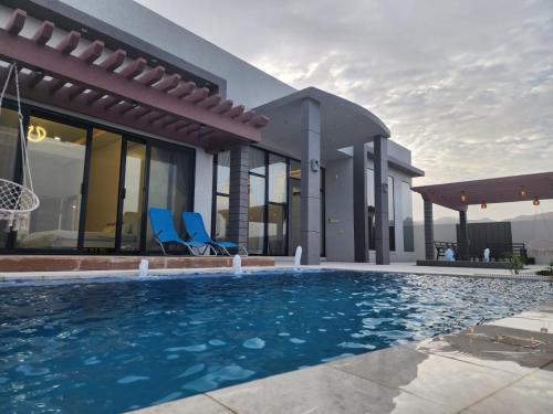 a villa with a swimming pool in front of a house at Skylight chalet in Nizwa