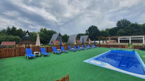 a group of chairs and a swimming pool on the grass at Doka Valea Sebesului A-Frame in Sebeşu