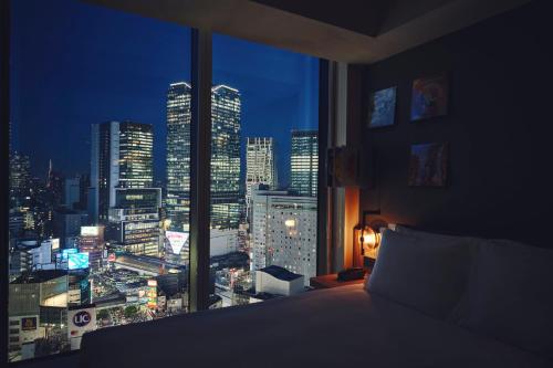 a bedroom with a view of a city at night at Hotel Indigo Tokyo Shibuya in Tokyo