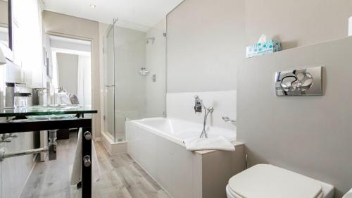 a white bathroom with a tub and a toilet at 801 Infinity 2 Bedroom Beachfront Apartment in Cape Town