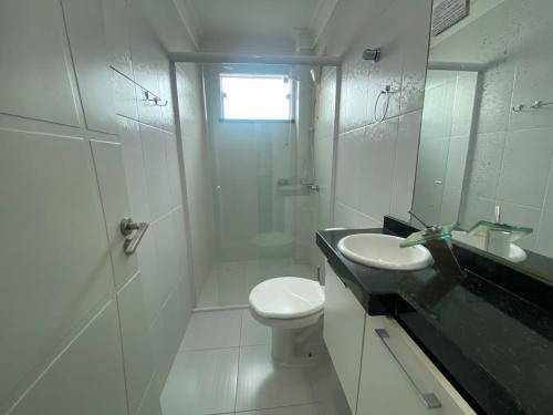 a white bathroom with a toilet and a sink at 182G - Excelente cobertura em condomínio completo in Bombinhas