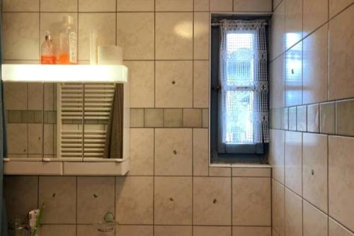 een badkamer met een raam en een betegelde muur bij Charmante maison individuelle in Les Verrières