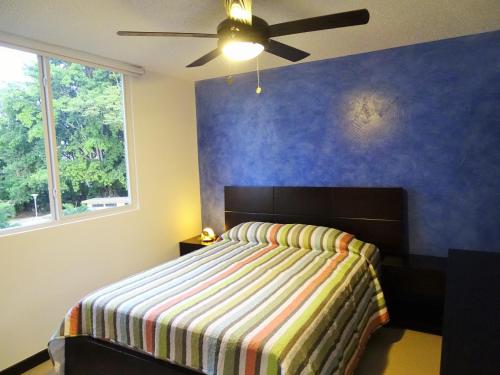 1 dormitorio con 1 cama con pared azul en Jaco Costa Linda Condo, en Jacó