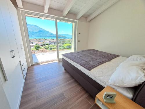 1 dormitorio con cama y ventana grande en Immobillario - Lakes Dream, en Domaso