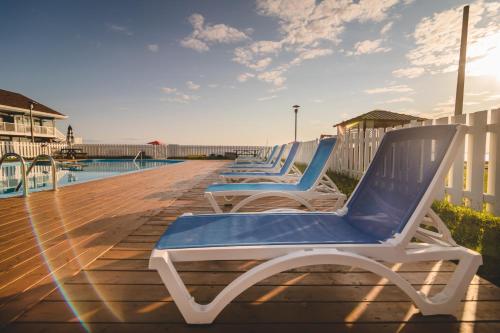 a row of chaise lounges on a deck by a pool at Riôtel Carleton-sur-Mer in Carleton sur Mer