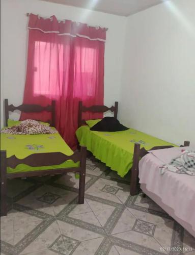 twee bedden in een kamer met een rood gordijn bij Casa em Diamantina in Diamantina