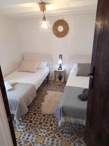 a bedroom with two beds and a table and a mirror at LA CASA AZUL in Chelva